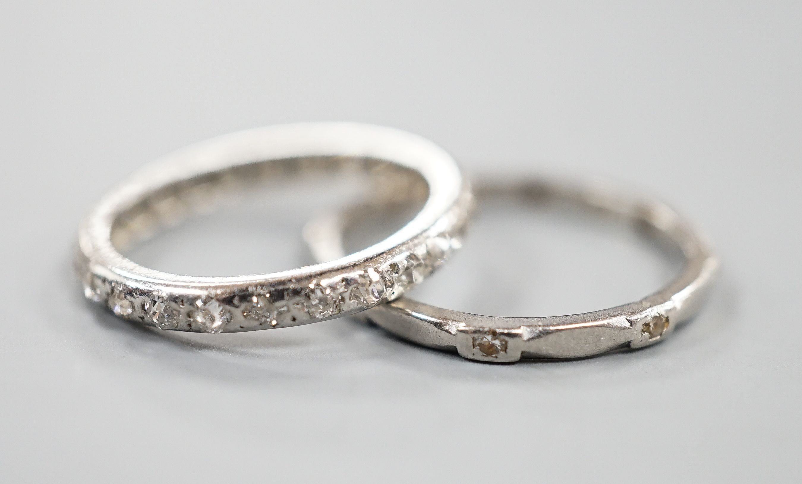A white metal and diamond chip set full eternity ring, size J and a white metal (stamped Pt) and diamond set eternity ring (two stones missing), size L, gross weight 4.2 grams.